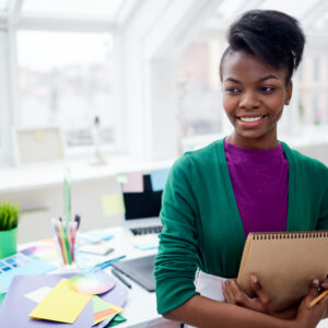 Smiling girl with notepad in studio of design